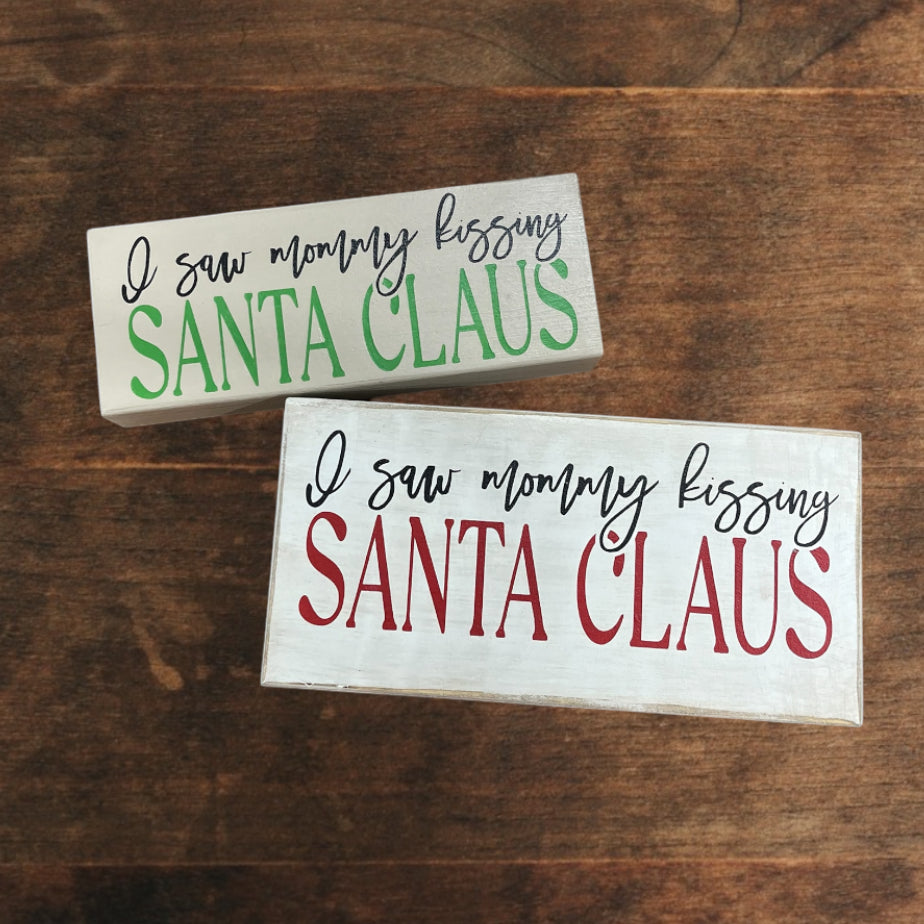 Saw mommy kissing Santa Claus Sign
