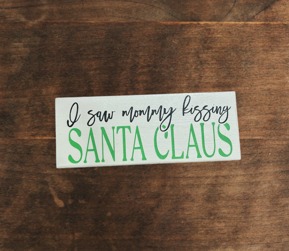 Saw mommy kissing Santa Claus Sign